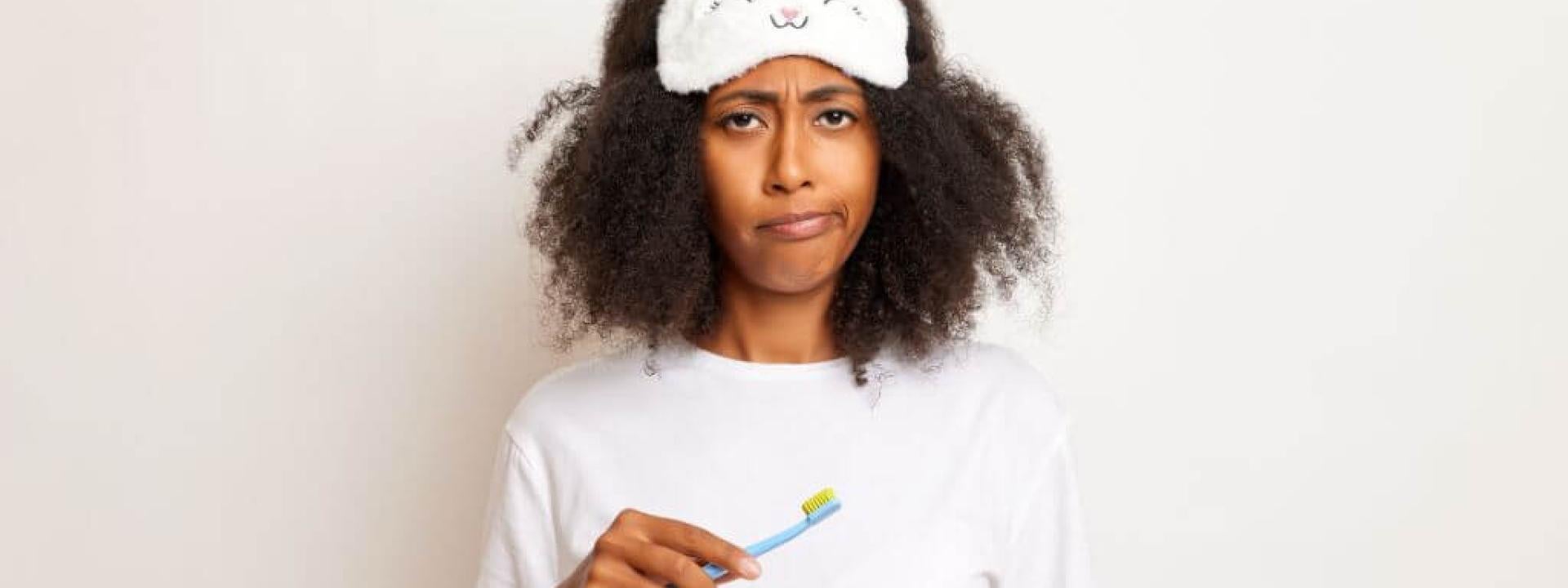 Woman tired from sleep brushing her teeth.
